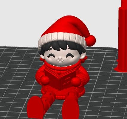 May include: A 3D rendered figurine of a character wearing a red Santa hat with a white brim and a red sweater, sitting down while holding an open red book. The character has black hair, a smiling face with closed eyes, and is positioned on a grid.