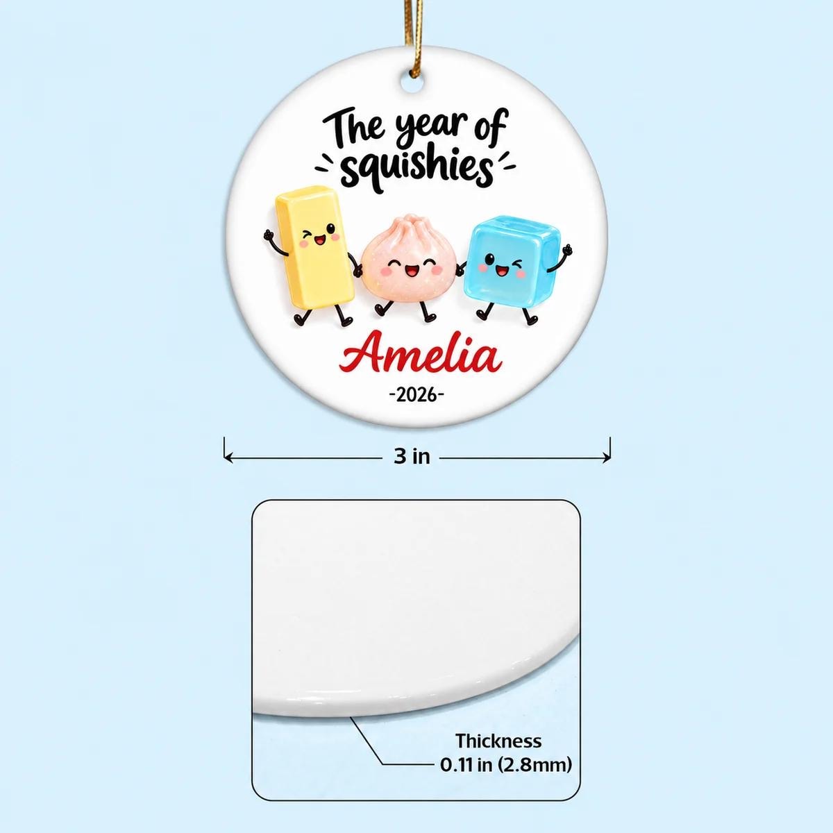 May include: A round white ceramic ornament featuring the text The year of squishies, the name Amelia, and the year 2026. It displays three cartoon characters and measures 3 inches in diameter with a thickness of 0.11 inches.
