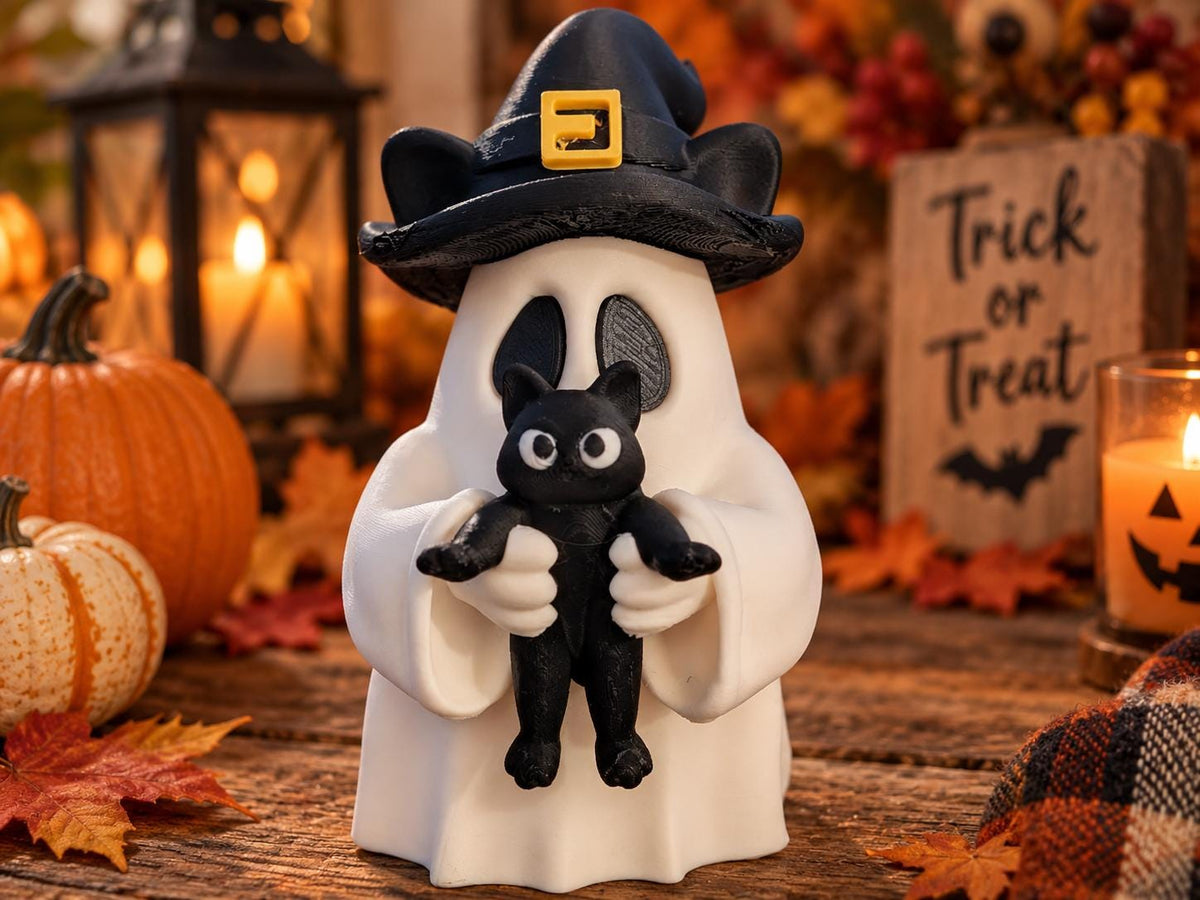 May include: A white ghost figurine wearing a black witch hat with a yellow buckle, holding a small black cat. The ghost has large oval eye cutouts and the cat has wide white eyes. The figure is smooth and stands upright on a flat surface.