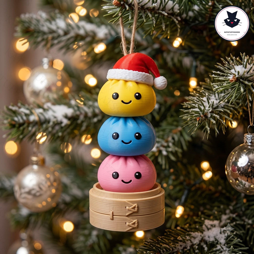 May include: A hanging Christmas ornament featuring a stack of three round, smiling dumpling figures in yellow, blue, and pink. The top yellow dumpling wears a small red and white Santa hat. The stack rests on a light brown, circular bamboo steamer base.