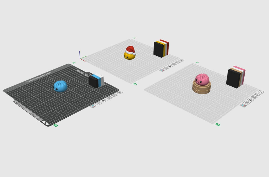 May include: A digital 3D modeling interface displaying three distinct build plates. One plate features a blue dumpling, another a yellow dumpling with a Santa hat, and the third a pink dumpling in a bamboo steamer, each with a color-coded block.