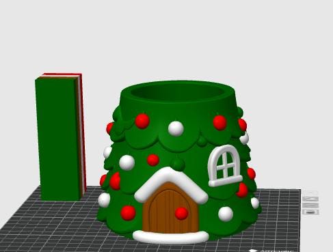 May include: A green, cone-shaped container designed like a Christmas tree, featuring a brown arched door with white trim, a white window, and scattered red and white spherical ornaments. A tall, rectangular green block stands to the left.