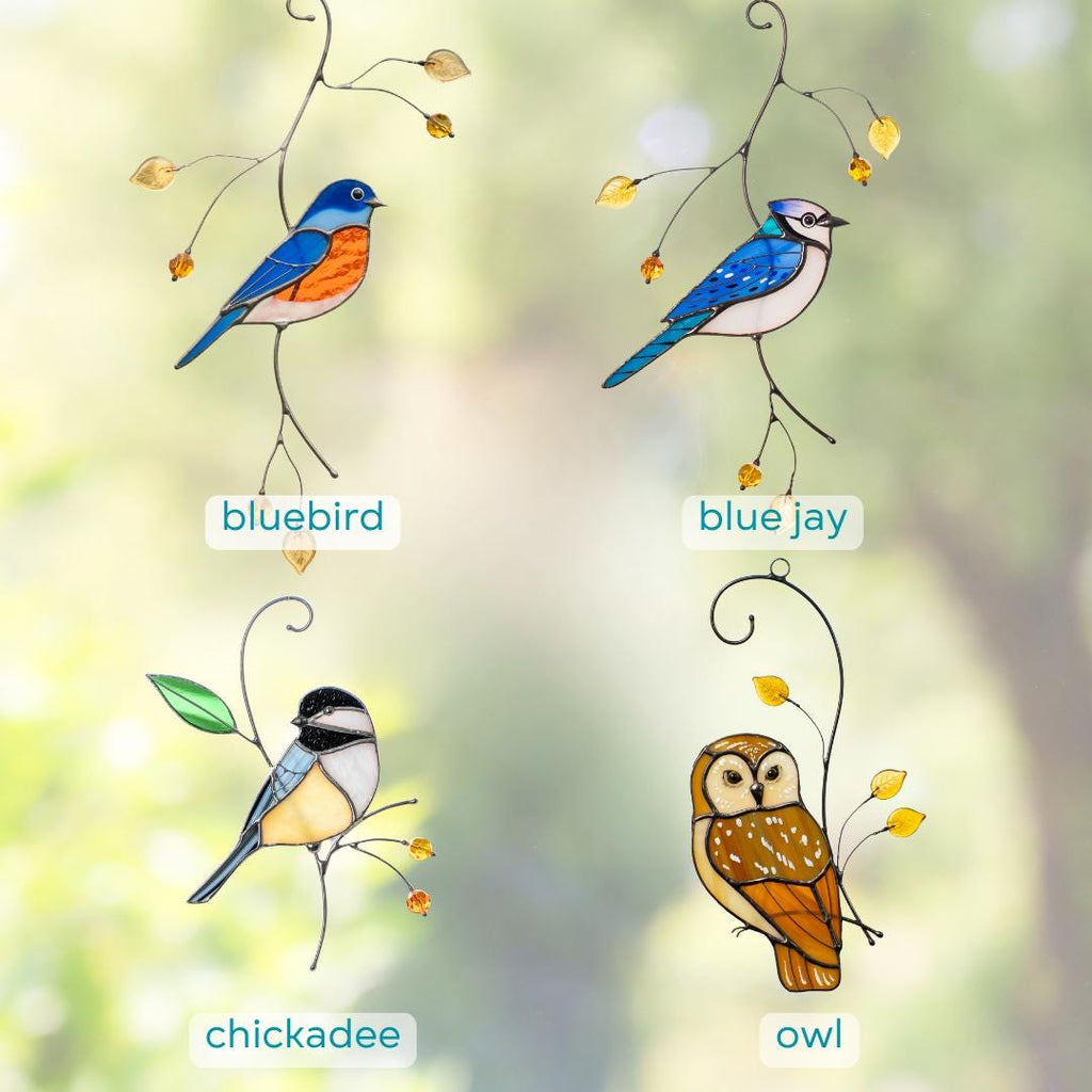 Stained glass bird suncatchers featuring a bluebird, blue jay, chickadee, and owl, hanging in front of a blurred garden view.