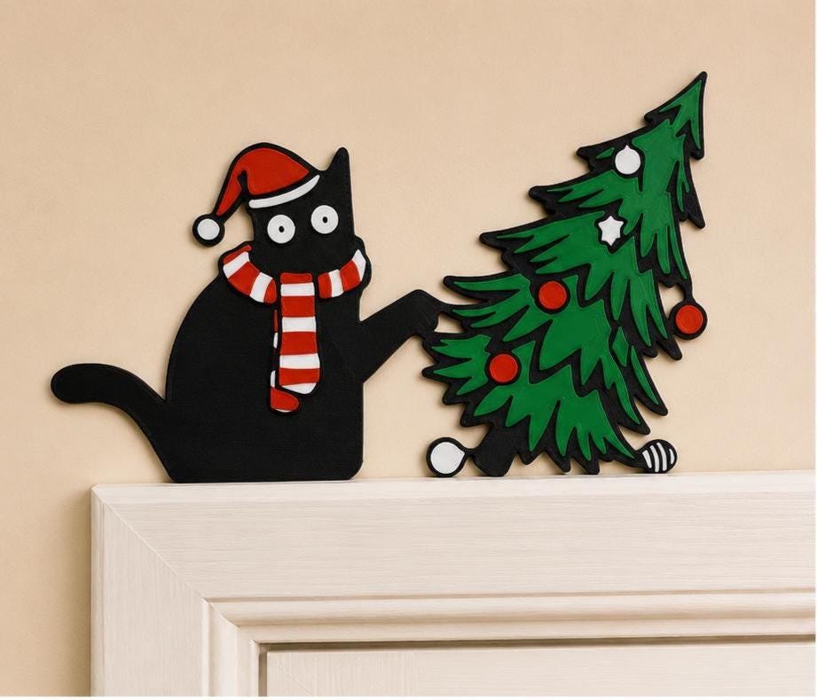 May include: A flat, decorative wall cutout featuring a black cat wearing a red and white Santa hat and a matching striped scarf. The cat is reaching out with one paw toward a green Christmas tree decorated with red and white circular ornaments.