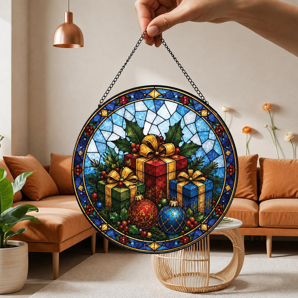 May include: A circular stained glass suncatcher featuring a festive holiday scene with three wrapped gift boxes in red, green, and blue, surrounded by holly leaves, berries, and two decorative ornaments, all enclosed in a blue geometric border.