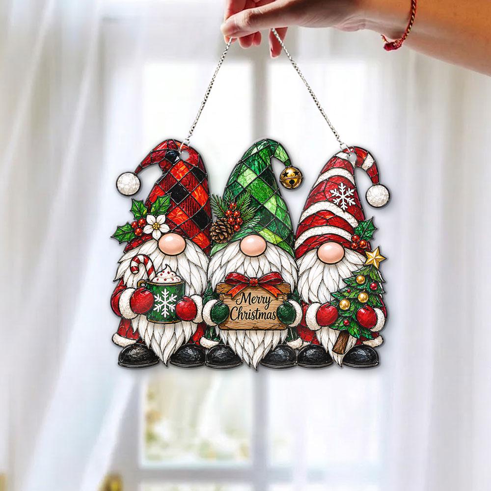 May include: A hanging ornament featuring three gnomes with white beards. The left gnome wears a red and black plaid hat, the center gnome a green plaid hat with a sign reading Merry Christmas, and the right gnome a red and white striped hat.