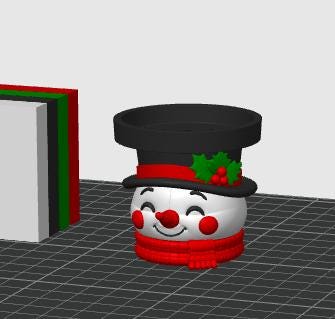 May include: A snowman-shaped planter featuring a white face with red cheeks and a red nose, wearing a black top hat adorned with a red band and green holly leaves with red berries. The base of the snowman is wrapped in a textured red scarf.