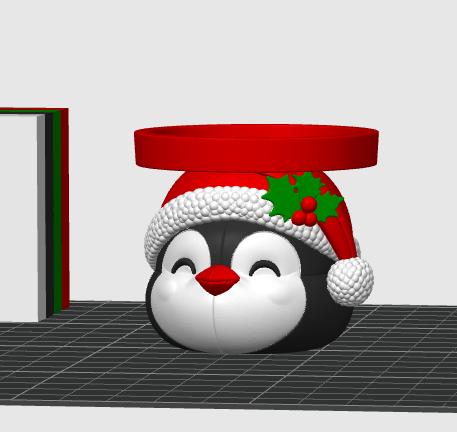 May include: A black and white penguin-shaped container featuring a red Santa hat with a white textured trim and green holly leaves with red berries. The penguin has a red beak and closed eyes, topped with a flat, circular red tray platform.