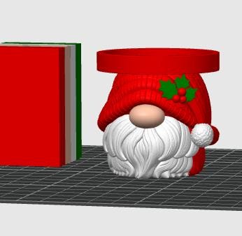 May include: A 3D rendered gnome-shaped container featuring a red hat with a green holly leaf and red berry accent, a large beige nose, and a white beard. Beside it stands a rectangular block with vertical red, white, and green stripes.