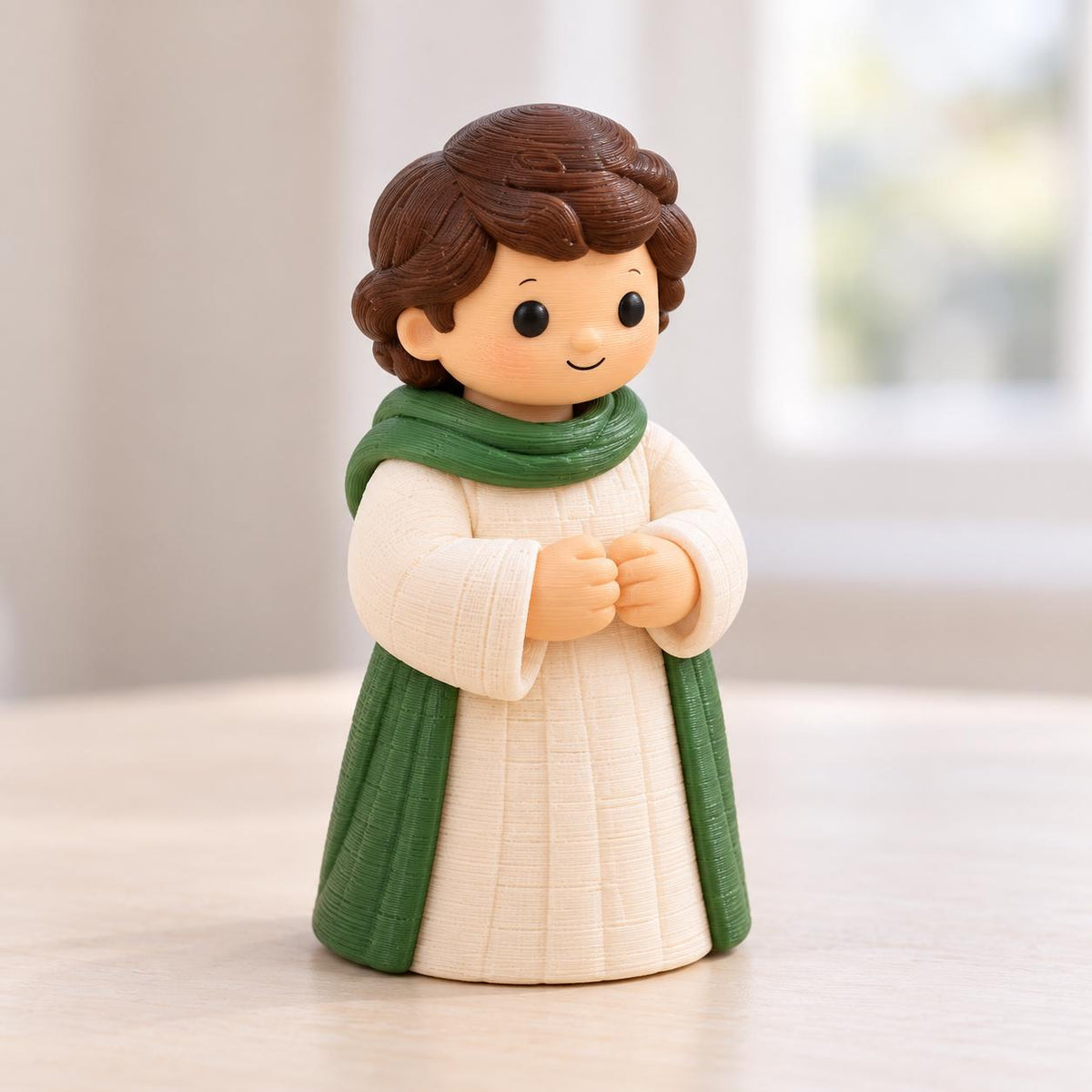 May include: A small figurine of a person with brown hair, wearing a cream-colored robe with a textured grid pattern and a green scarf draped over the shoulders. The figure has a simple facial expression with black eyes and a small smile.