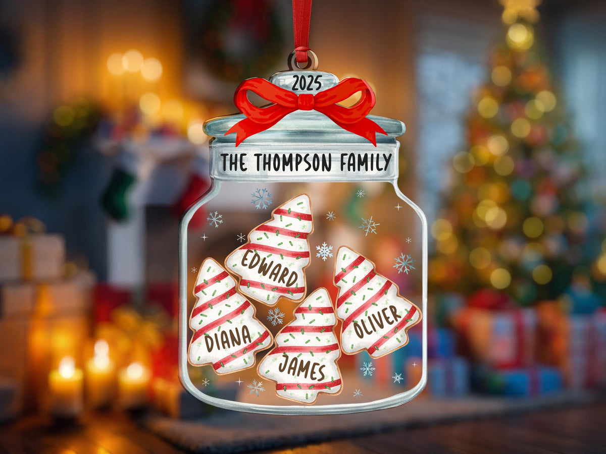 May include: A clear glass jar ornament featuring a red ribbon at the top with the year 2025. The jar is labeled THE THOMPSON FAMILY and contains four white Christmas tree-shaped cookies with red stripes and the names Edward, Diana, James, and Oliver.