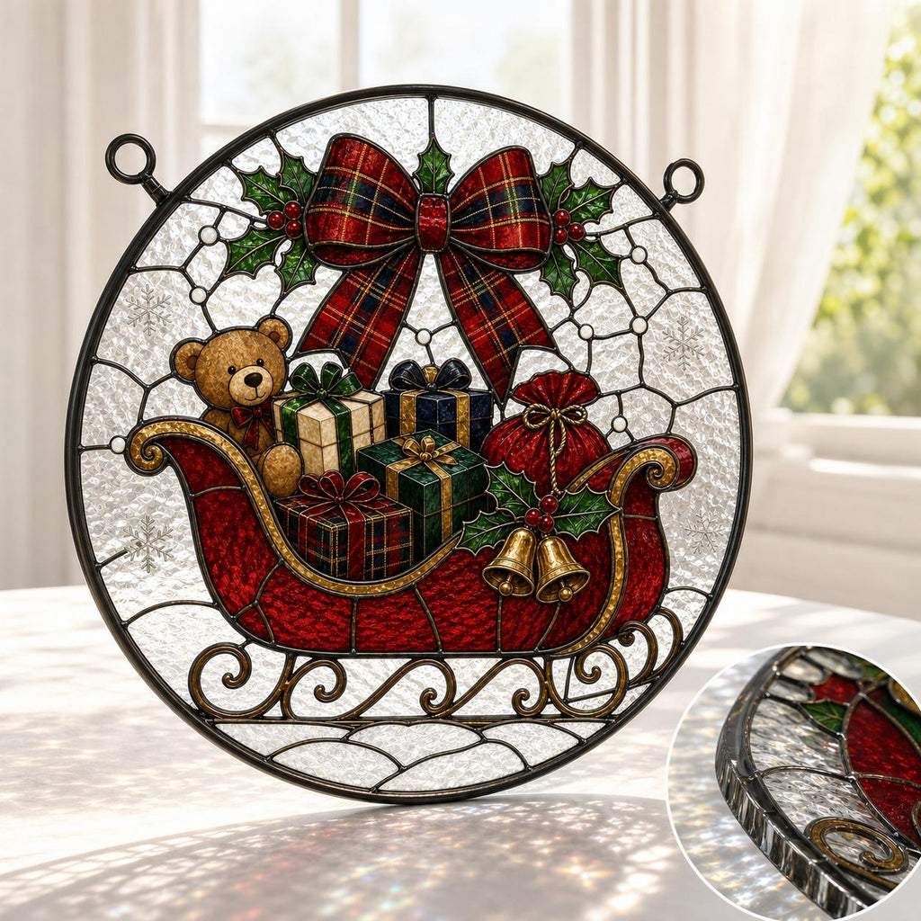 May include: A circular stained glass suncatcher featuring a red sleigh filled with wrapped gifts and a teddy bear. A large red plaid bow sits above the sleigh, accented by green holly leaves and red berries. Two gold bells hang from the side.