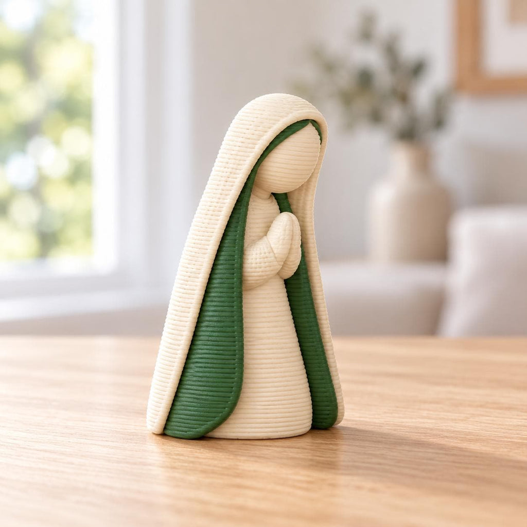 May include: A figurine of a person with hands clasped in prayer, featuring a textured, ribbed surface. The figure wears a cream-colored head covering and robe with a deep green interior lining, standing in a vertical, upright position.