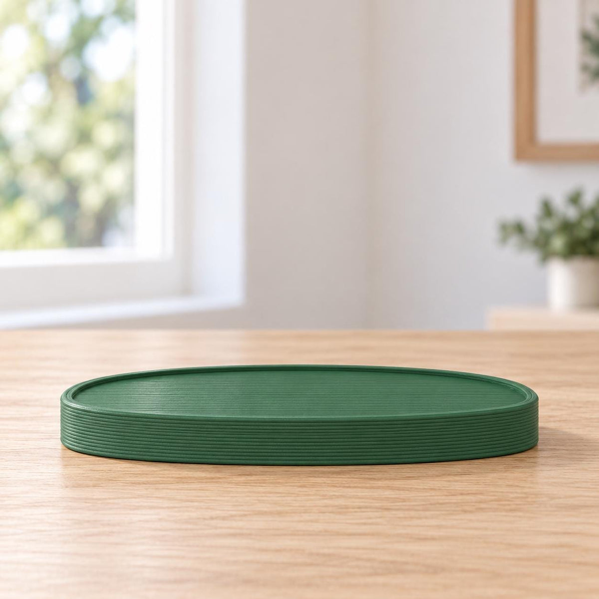May include: A dark green oval tray featuring a series of fine, horizontal ribbed lines along its outer edge and a smooth, flat surface. The tray has a low profile and a consistent, solid matte finish throughout its entire structure.