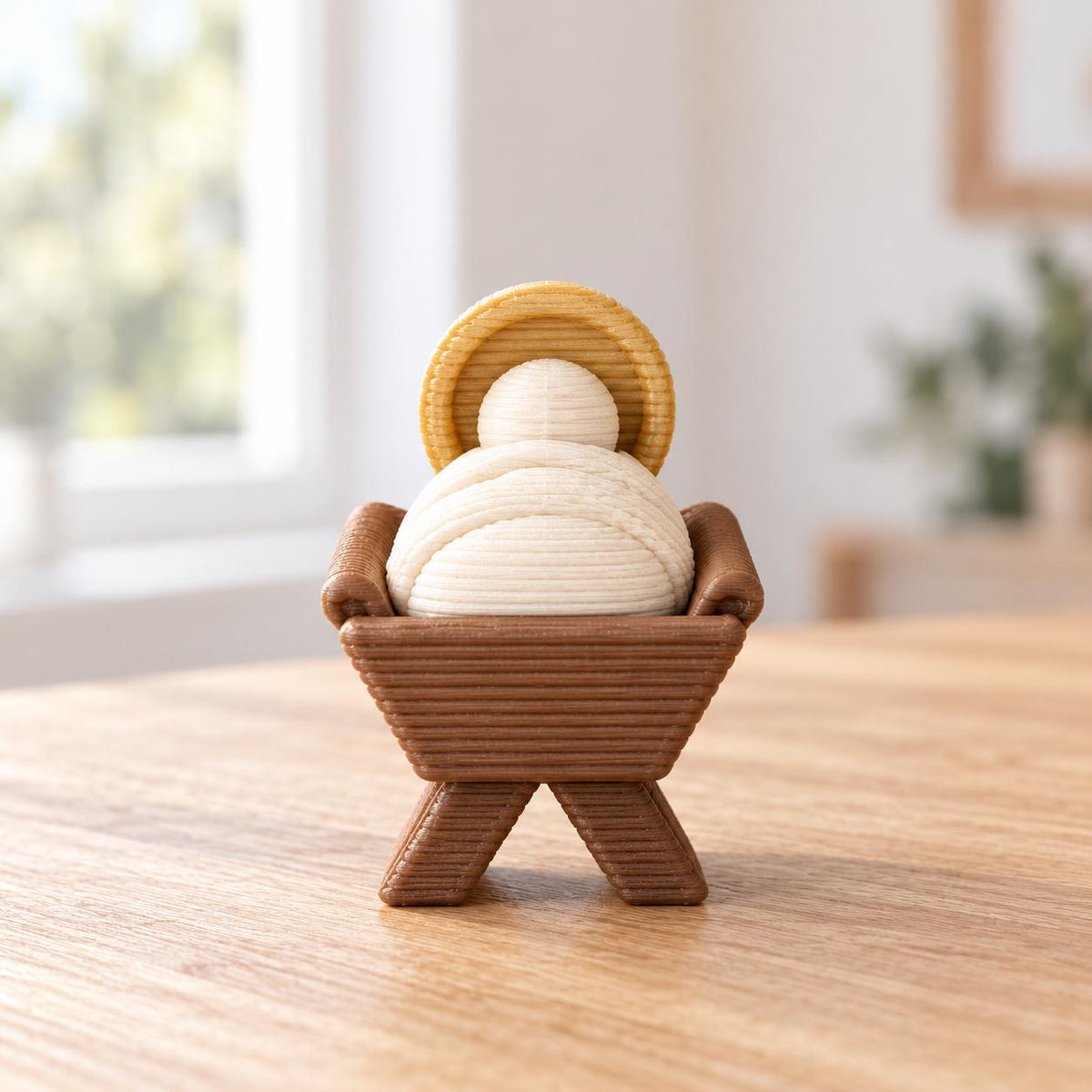 May include: A 3D-printed figurine of a swaddled infant in a manger. The infant is cream-colored with a golden halo behind the head. The manger is brown with a textured, ribbed surface finish visible on all components of the small object.