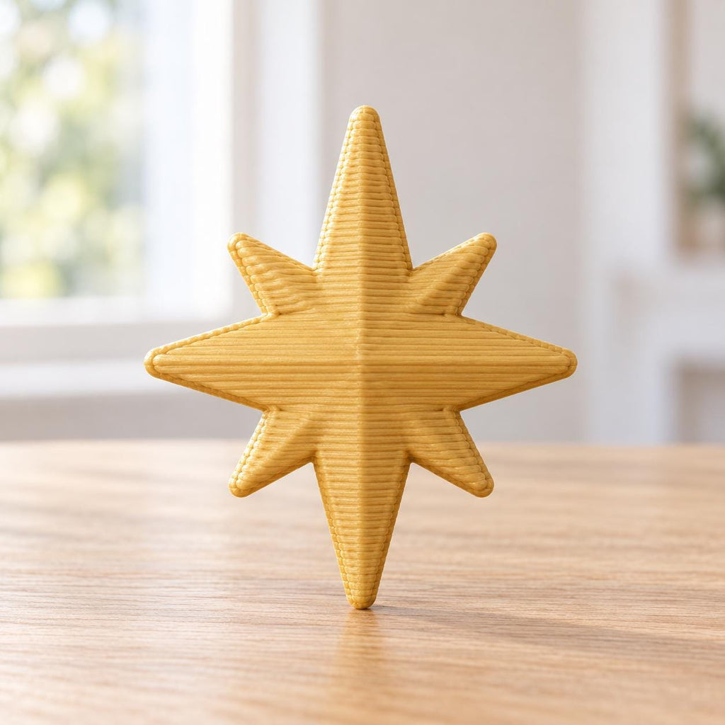 May include: A golden yellow, eight-pointed star ornament featuring a distinct ribbed, linear texture across its surface. The star has a symmetrical design with four long points and four shorter points, creating a classic geometric shape.
