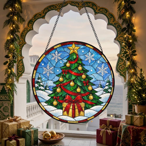 May include: A circular stained glass suncatcher featuring a green Christmas tree decorated with gold ornaments, a red ribbon, and a yellow star topper. The scene includes white snowflakes against a blue sky and a gift box at the base.