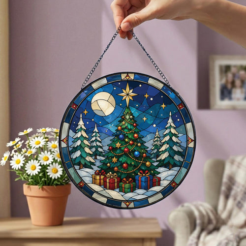 May include: A circular stained glass suncatcher featuring a festive Christmas tree scene with a bright star topper, colorful ornaments, and wrapped gifts at the base. The design includes a snowy landscape, pine trees, and a moon, suspended by a chain.