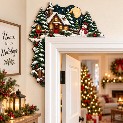 May include: A decorative wooden door corner topper featuring a winter scene with a snow-covered cabin, evergreen trees, a snowman, and a full moon against a dark blue night sky. The design includes a lit lantern and festive holly accents.