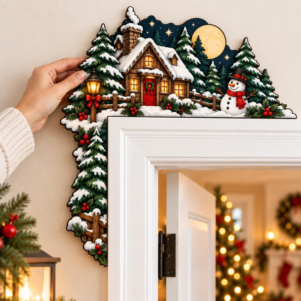 May include: A decorative wooden door corner topper featuring a winter scene with a snow-covered cabin, evergreen trees, a snowman with a red scarf, a glowing street lamp, and a full moon against a dark blue night sky with stars.