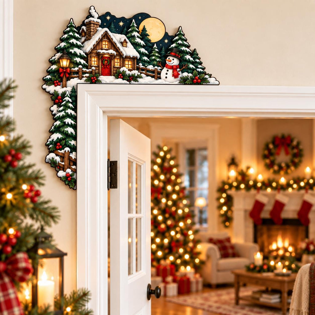 May include: A decorative wooden door corner sign featuring a winter scene with a snow-covered cabin, a snowman, and evergreen trees. The illustration includes a full moon in a dark blue night sky, with red berries and green foliage accents.