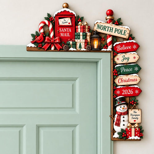 May include: A Christmas-themed door corner decoration featuring a red Santa Mail box, a North Pole sign, and stacked gift boxes. It includes a lantern, a candy cane, a cardinal, and a snowman with signs reading Believe, Joy, Peace, Christmas, 2026, and The Thompson Family.
