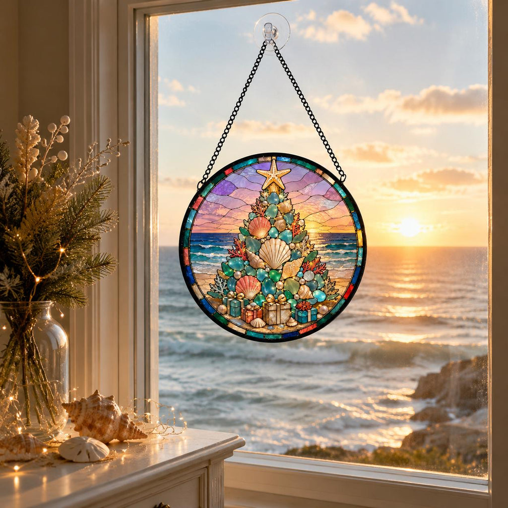 May include: A circular stained glass suncatcher featuring a Christmas tree composed of various seashells and sea glass, topped with a starfish. The design includes small gift boxes at the base, all suspended by a black metal chain against a sunset.