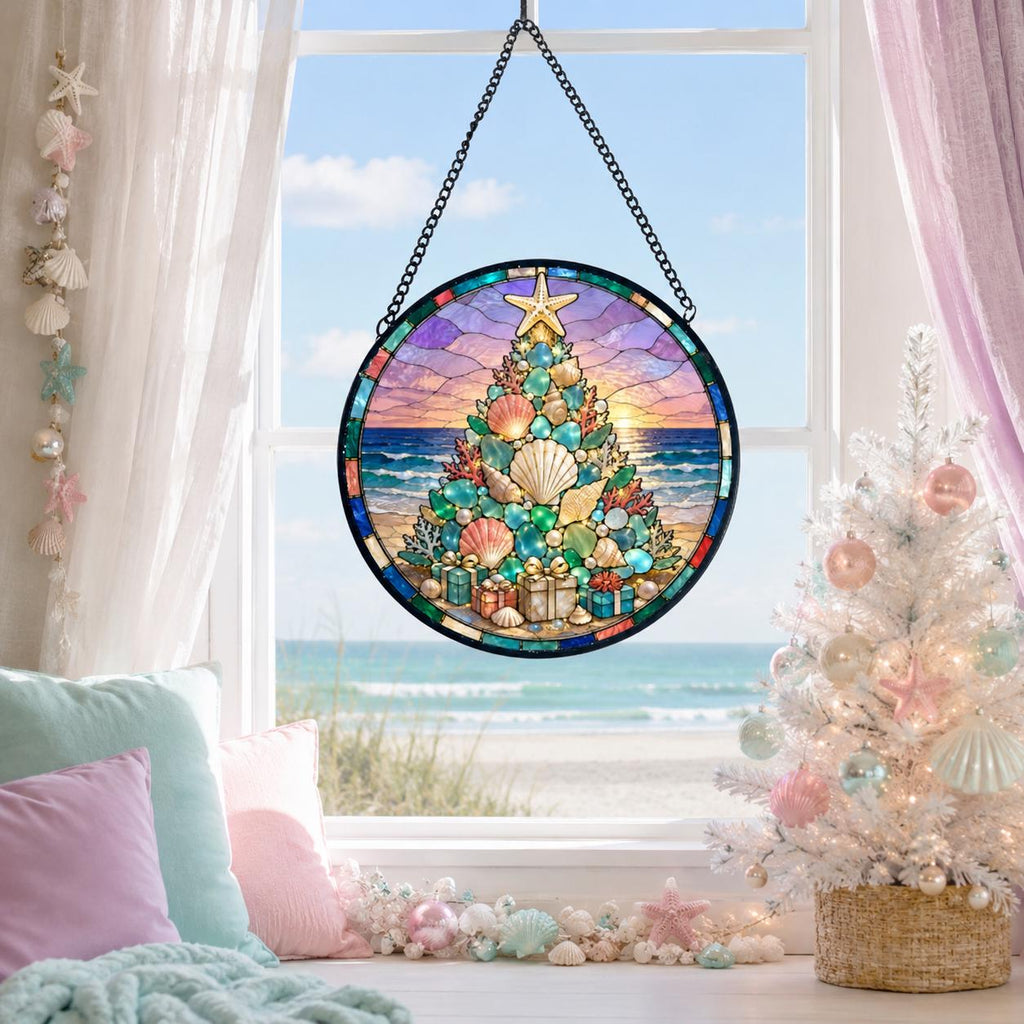 May include: A circular stained glass suncatcher featuring a Christmas tree composed of various seashells and sea glass. The tree is topped with a starfish and surrounded by small gift boxes, set against a backdrop of a beach at sunset.