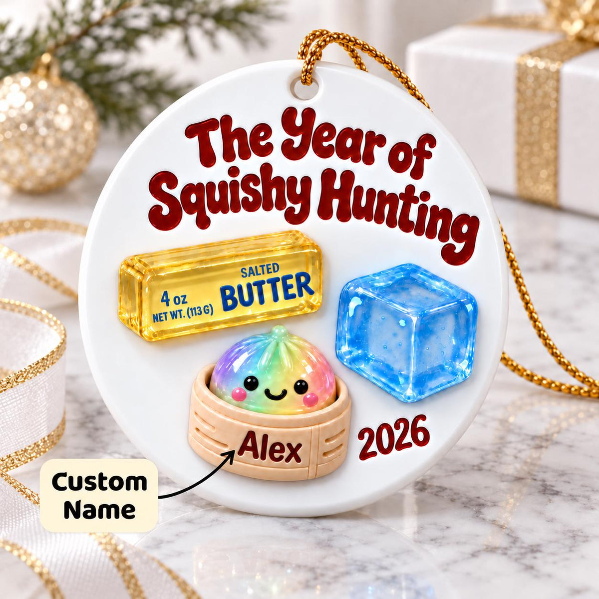 May include: A round white ceramic ornament featuring the red text The Year of Squishy Hunting, a yellow stick of 4 oz salted butter, a blue ice cube, and a rainbow-colored dumpling in a steamer basket with the custom name Alex and the year 2026.