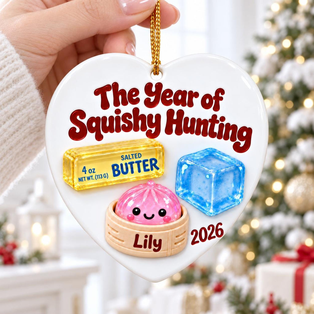 May include: A heart-shaped white ceramic ornament featuring the text The Year of Squishy Hunting, a yellow stick of 4 oz salted butter, a blue ice cube, and a pink dumpling in a bamboo steamer with the name Lily and the year 2026 printed below.
