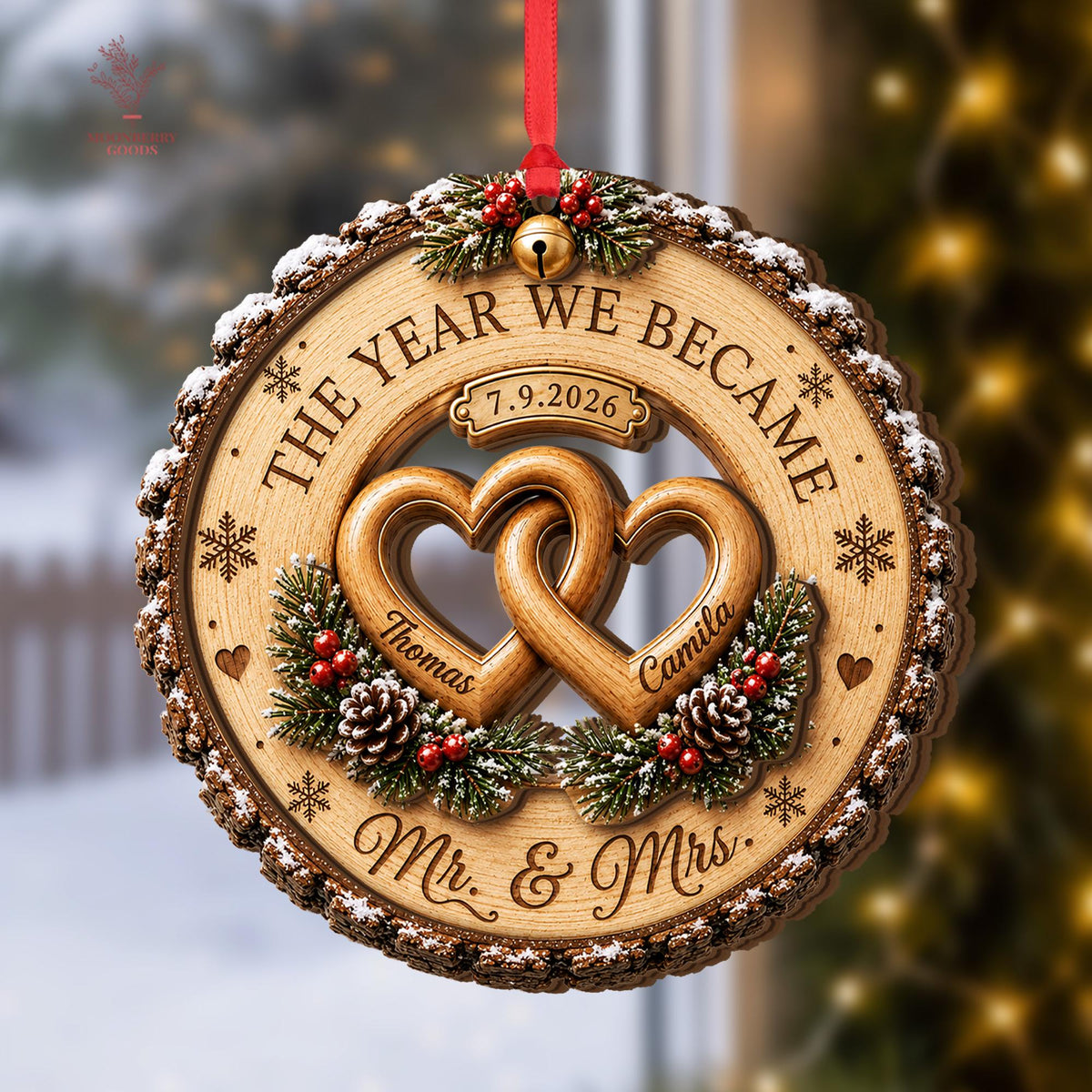 May include: A round wooden ornament with bark edges featuring two interlocking hearts, pine branches, pinecones, and red berries. Text reads THE YEAR WE BECAME, 7.9.2026, Thomas, Camila, and Mr. & Mrs. A small gold bell hangs from a red ribbon.