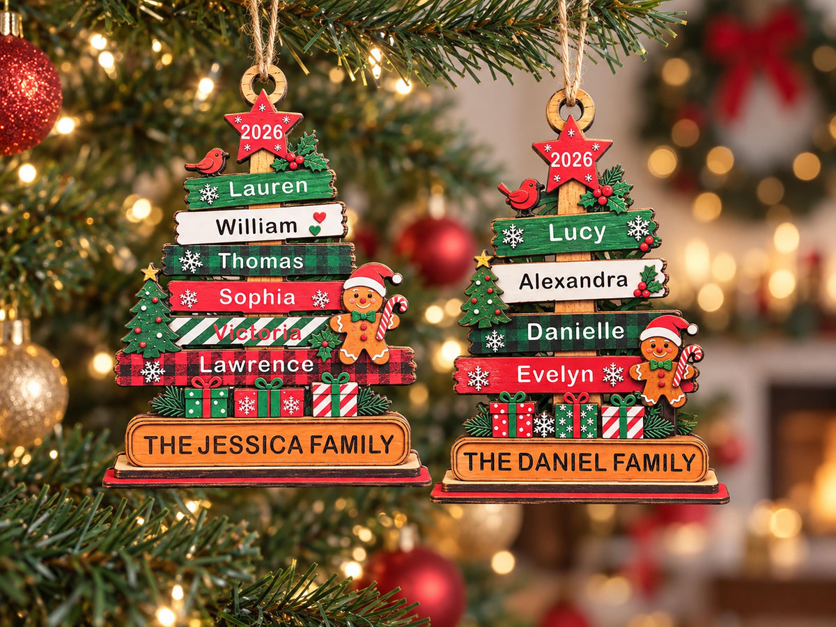 May include: Two wooden Christmas tree ornaments featuring stacked horizontal planks with names, a red star at the top labeled 2026, a gingerbread person, and gift boxes. The base of each ornament is engraved with THE JESSICA FAMILY or THE DANIEL FAMILY.
