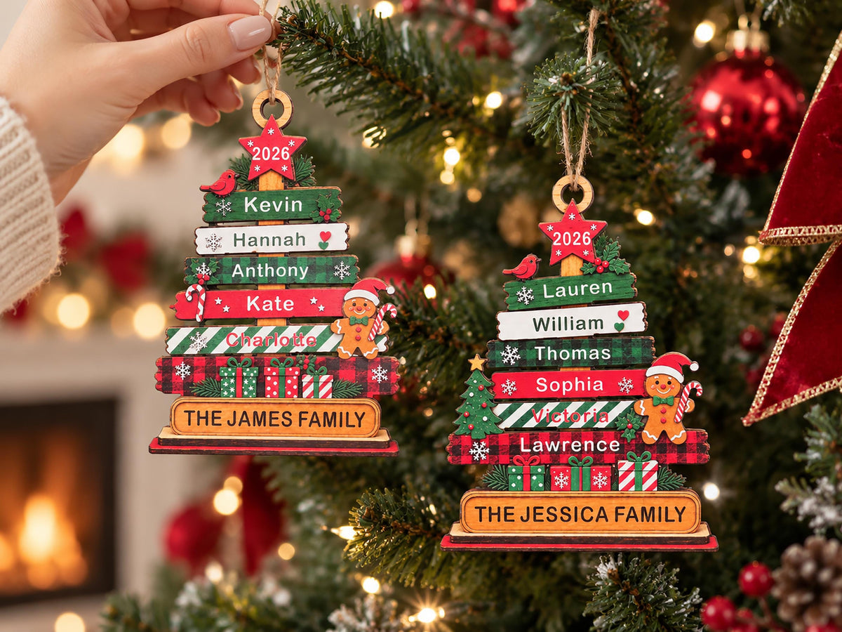 May include: Two wooden Christmas tree ornaments featuring stacked horizontal planks with names, the year 2026 on a red star, a gingerbread person, and gift box graphics. One ornament is labeled THE JAMES FAMILY and the other THE JESSICA FAMILY.