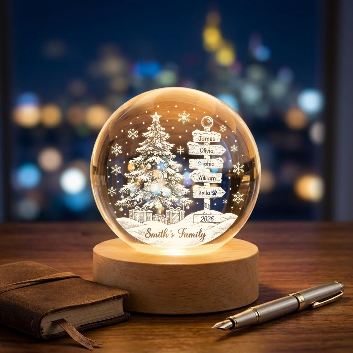 May include: A spherical glass ornament on a round wooden base featuring an etched Christmas tree, gift boxes, and a signpost with the names James, Olivia, Sophia, William, and Bella. The text 2026 and Smith's Family is engraved on the glass.