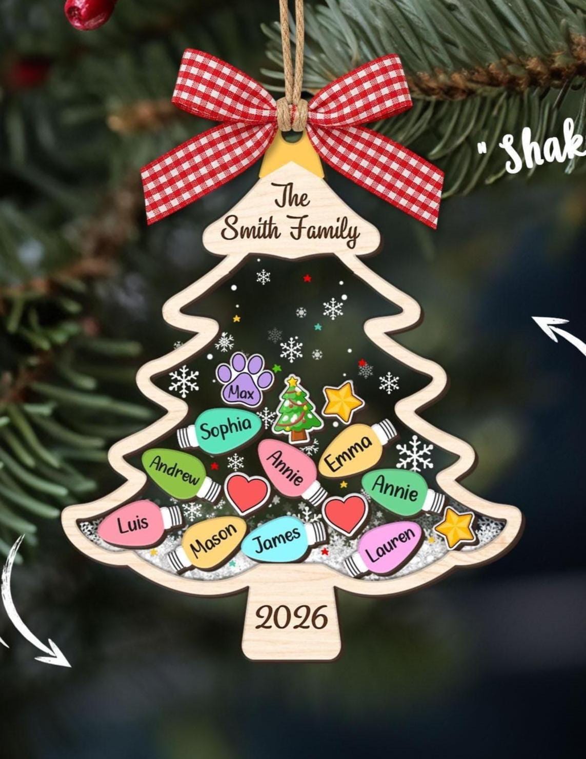May include: A wooden Christmas tree-shaped shaker ornament featuring a red and white gingham bow, the text The Smith Family, and 2026. The center contains colorful light bulb shapes with names, a paw print, a heart, and a star, all over white glitter.