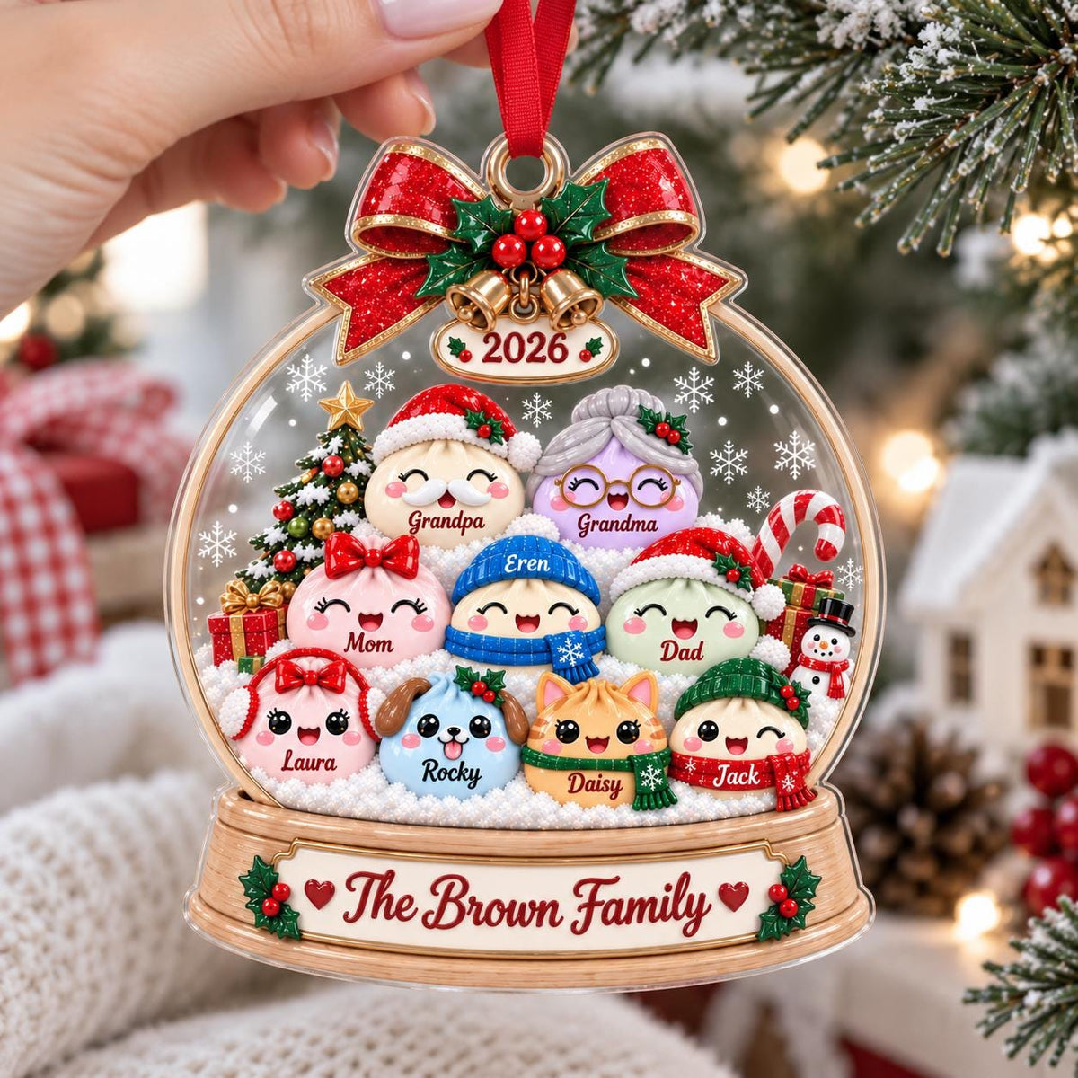 May include: A clear, globe-shaped Christmas ornament featuring a group of cartoon characters labeled Grandpa, Grandma, Mom, Eren, Dad, Laura, Rocky, Daisy, and Jack. The base displays the text The Brown Family and the year 2026 with a red bow.