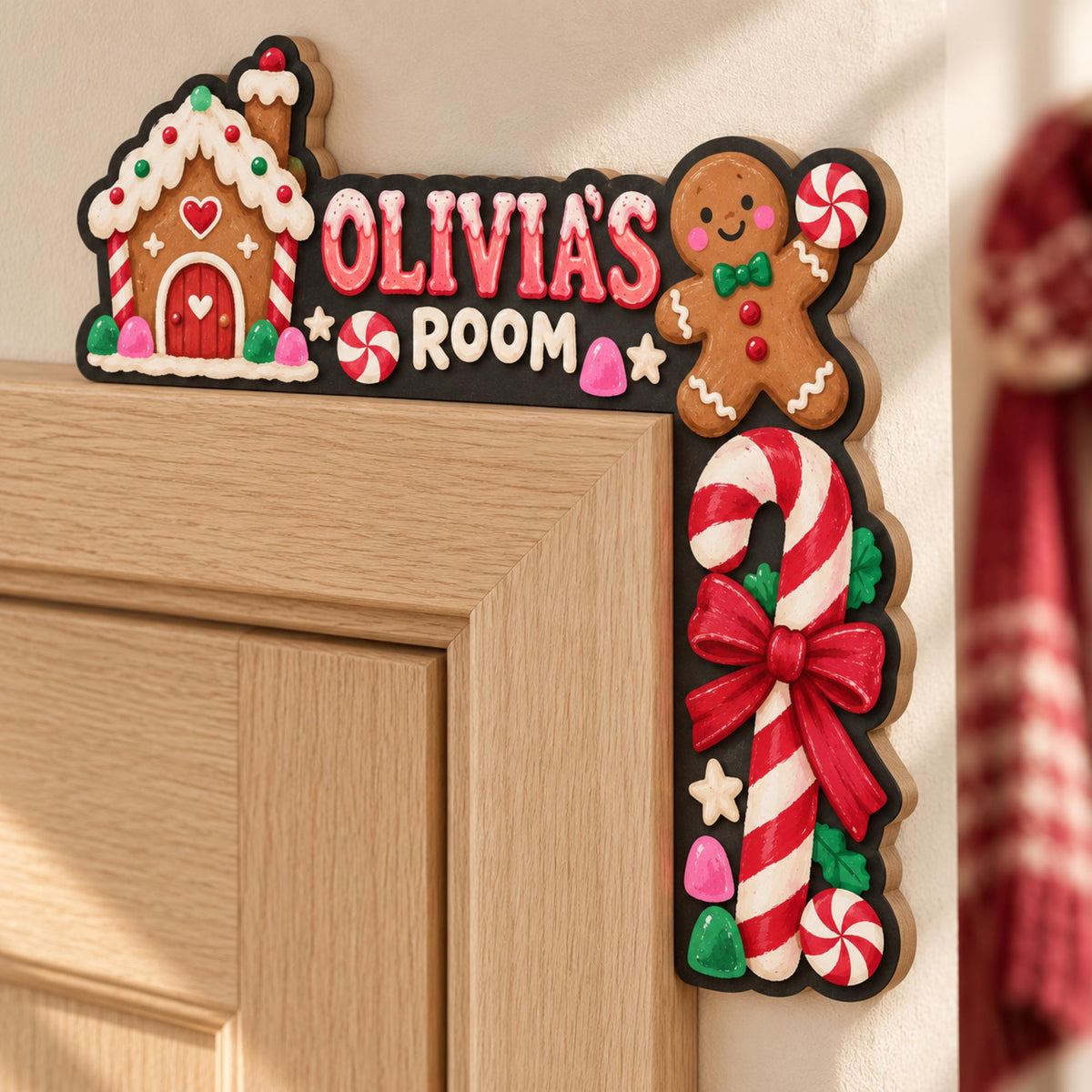 May include: A black L-shaped door corner sign featuring a gingerbread house, a gingerbread person, and a candy cane. The text reads OLIVIA'S ROOM in pink and white letters. The design includes red and white peppermint candies and gumdrops.