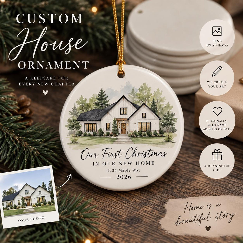 May include: A round white ceramic ornament featuring a watercolor illustration of a house with a dark roof and white siding. The text reads Our First Christmas IN OUR NEW HOME 1234 Maple Way 2026. It hangs from a gold string against a pine branch background.