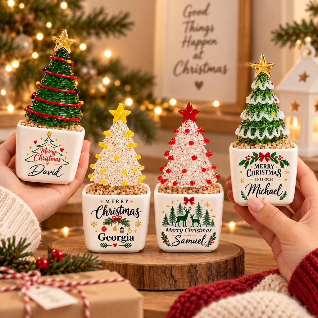 May include: Four small decorative Christmas tree ornaments in white square ceramic pots. Each tree is made of colorful beads with a star topper. The pots feature festive graphics, holiday text, and personalized names: David, Georgia, Samuel, and Michael.