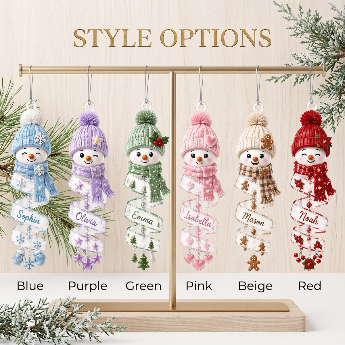 May include: Six hanging snowman ornaments in blue, purple, green, pink, beige, and red. Each snowman wears a matching knit hat and scarf, with a spiral ribbon base featuring names: Sophia, Olivia, Emma, Isabella, Mason, and Noah. Text reads STYLE OPTIONS.