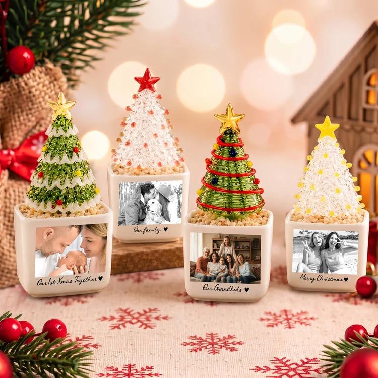 May include: Four square white ceramic planters, each holding a miniature decorative Christmas tree topped with a star. Each planter features a black and white printed photograph and text, including "Our 1st Xmas Together," "Our family," "Our Grandkids," and "Merry Christmas."