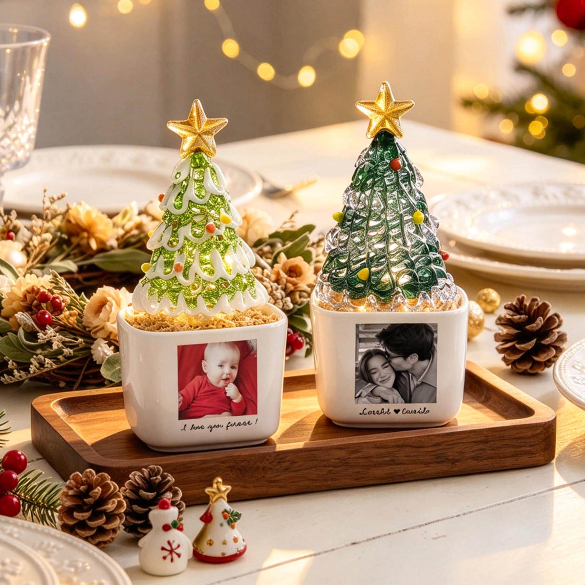 May include: Two square white ceramic planters featuring custom photo prints and text, each topped with a decorative glass Christmas tree with a gold star topper. The planters sit on a rectangular wooden tray, illuminated by internal lights.