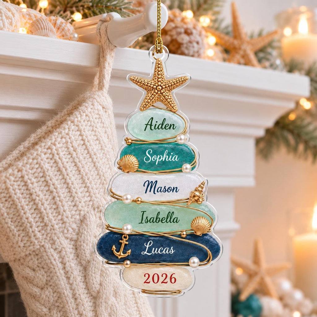 May include: A Christmas tree-shaped ornament featuring six stacked, smooth, rounded stones in shades of light green, teal, white, and dark blue. The stones are inscribed with the names Aiden, Sophia, Mason, Isabella, Lucas, and the year 2026.