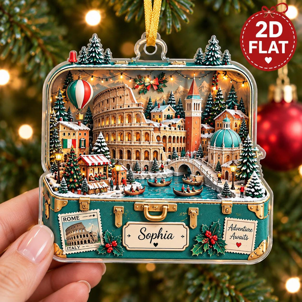 May include: A flat, rectangular Christmas ornament shaped like a suitcase, featuring a detailed 3D-style illustration of Rome with the Colosseum, a canal, and snowy trees. The suitcase exterior displays the text 'Rome Italy', 'Sophia', and 'Adventure Awaits'.