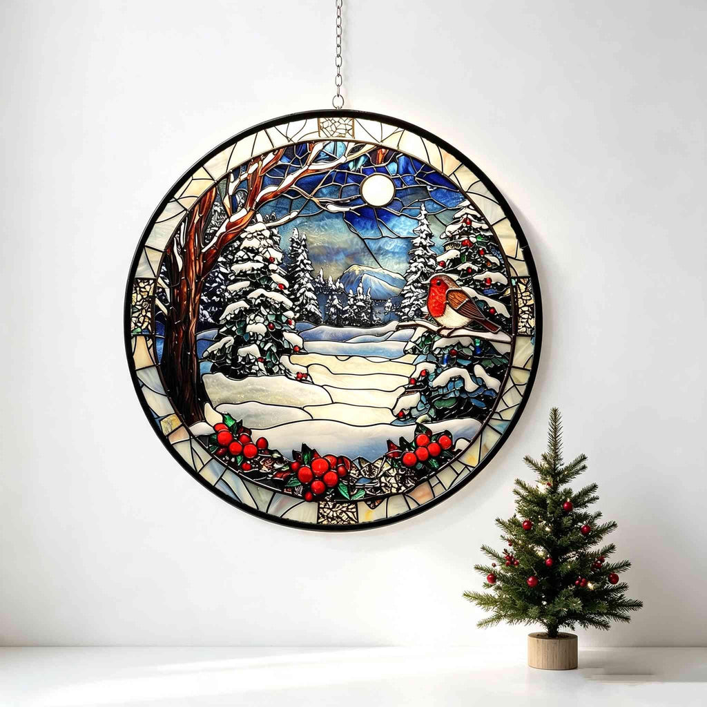 May include: A circular stained glass suncatcher featuring a winter landscape with a robin perched on a snow-covered branch. The scene includes evergreen trees, a bright moon in a blue sky, and clusters of red berries, all framed in black metal.