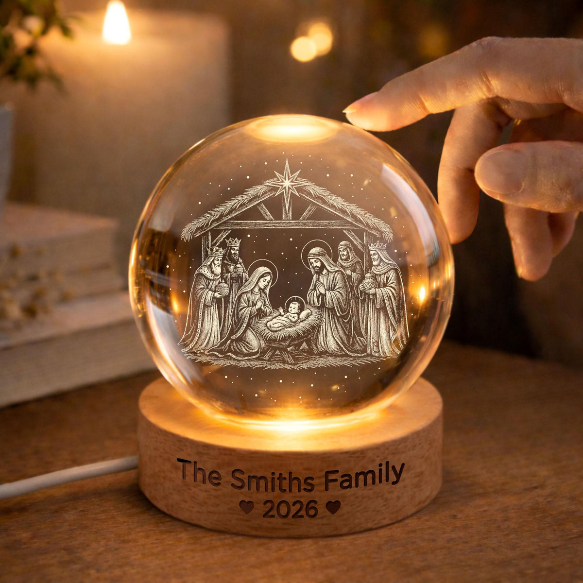 May include: A clear glass sphere featuring an internal laser-etched nativity scene with a star above a stable. The sphere rests on a round wooden base engraved with the text The Smiths Family 2026 and two small heart symbols.