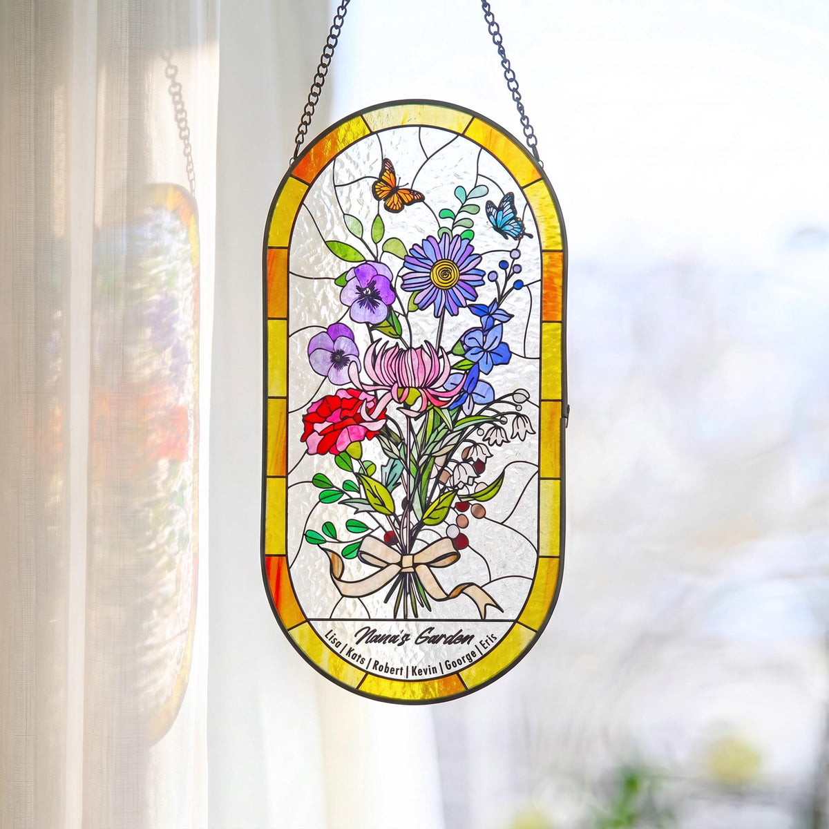May include: Stained glass window panel with a bouquet of colorful flowers, butterflies, and the text "Nana's Garden." The panel is framed in yellow and hangs from a chain. The flowers include red, purple, and blue blooms.