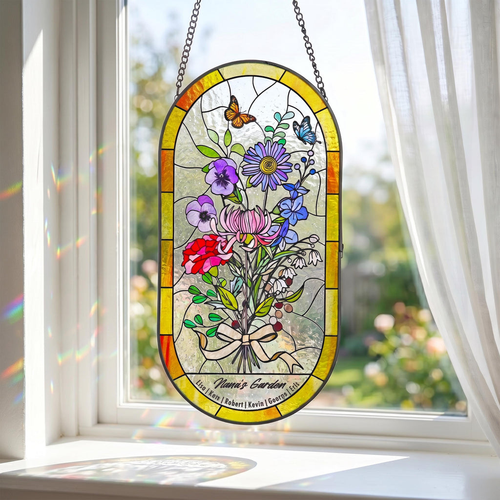 May include: Stained glass window panel with a floral bouquet design. The panel features a variety of colorful flowers, butterflies, and the text "Nana's Garden". The panel is framed in yellow and hangs from a chain.