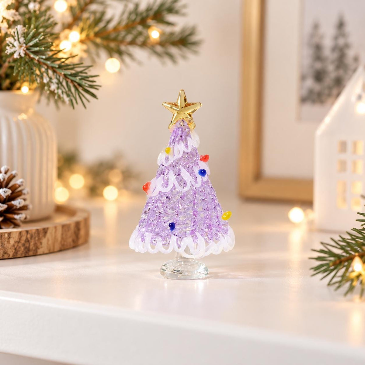 May include: A small, conical glass Christmas tree ornament in a light purple hue with a textured, beaded surface. It features a swirling white glass garland, small colorful glass bead accents, and a gold-colored star topper on a clear base.