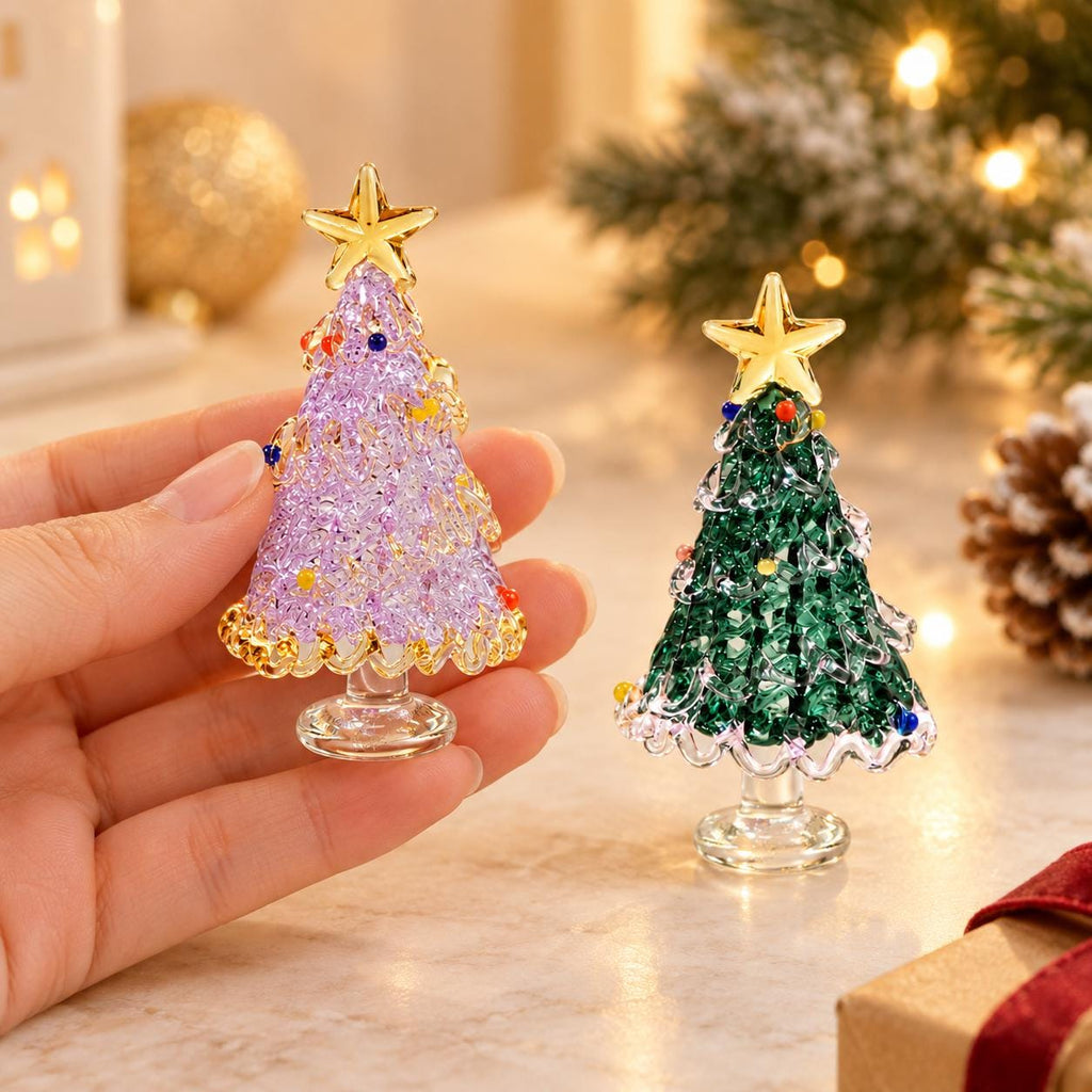 May include: Two miniature glass Christmas tree figurines, one in lavender and one in dark green, each featuring a textured, crystalline surface, small colorful glass bead accents, a clear glass base, and a polished gold-tone star topper.
